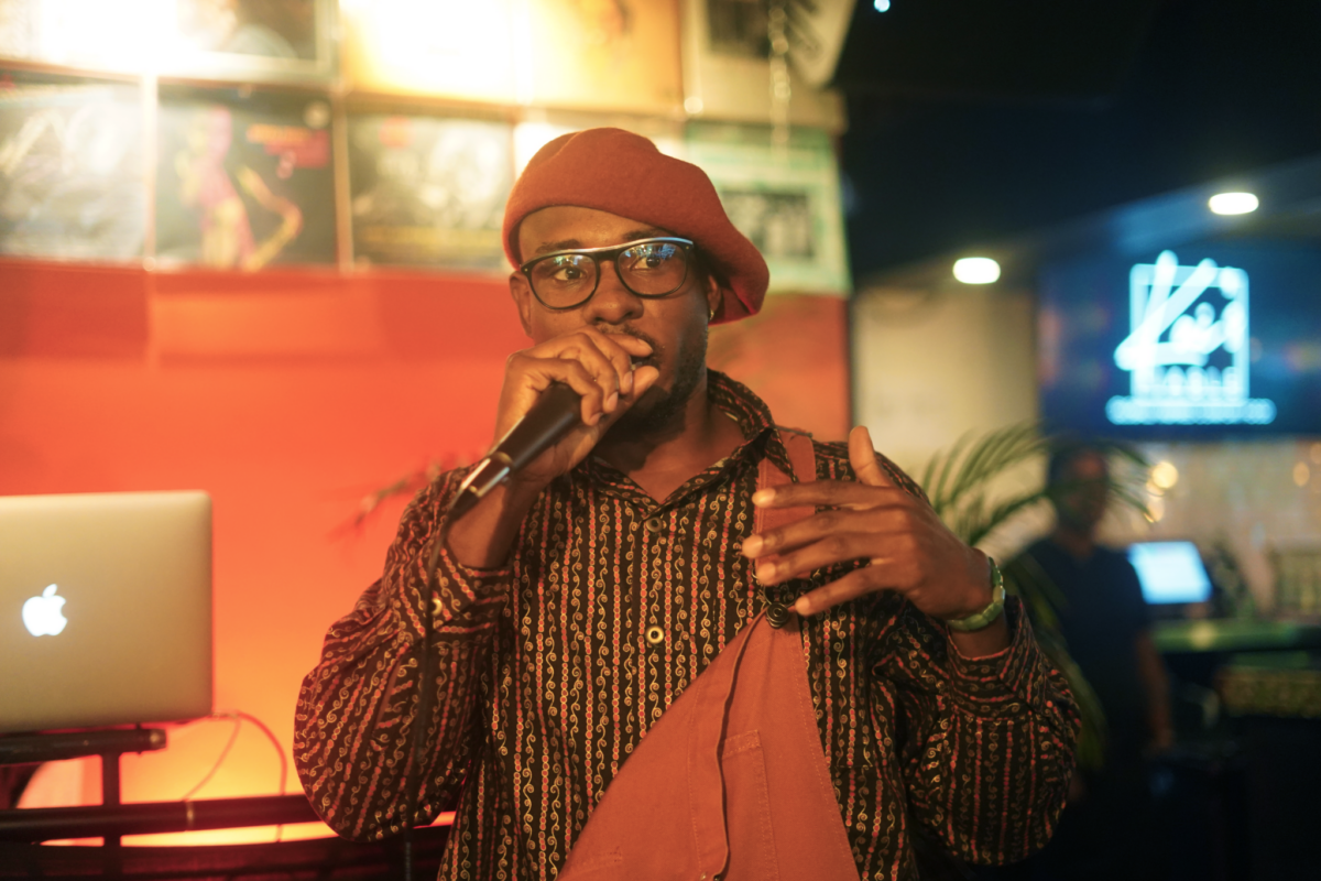 Photo of a black man in a red beret speaking into a microphone